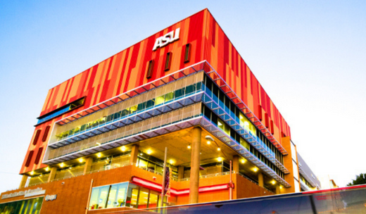 a bus driving past a tall red building.