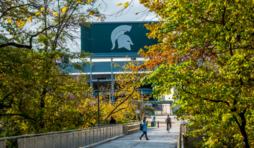 a person walking across a bridge with a sign in the background.