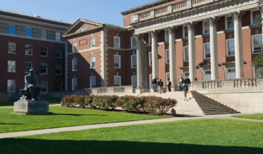 a group of people standing on a lawn in front of a building.