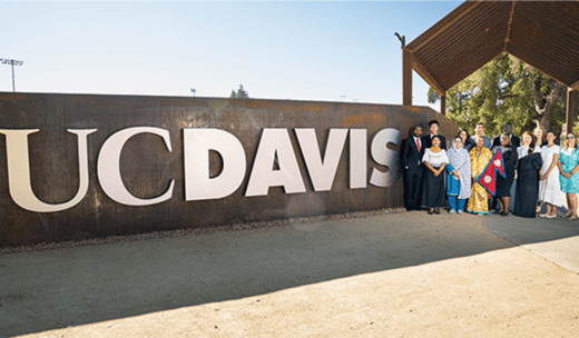a group of people standing in front of a uc davis sign.