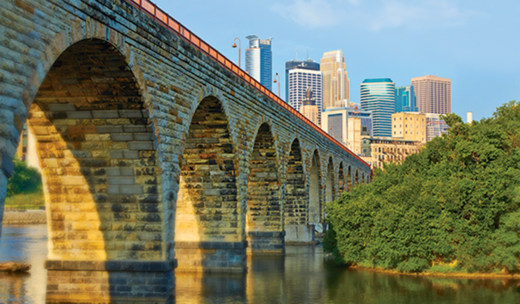 a bridge over a river with a city in the background.